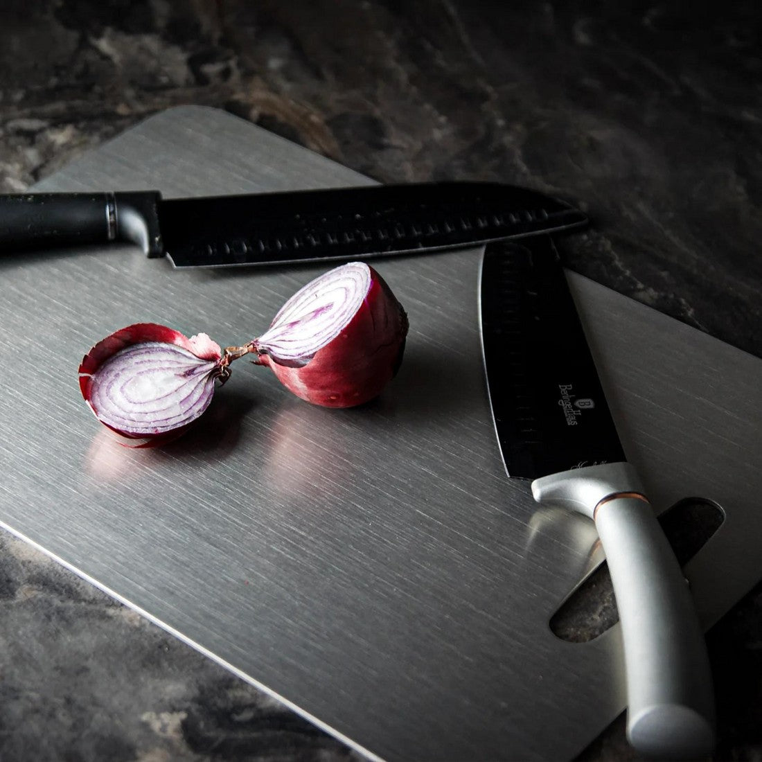 Knightsax Privateer 
®
 medical-grade titanium cutting board, silver, with two knives and a red onion.